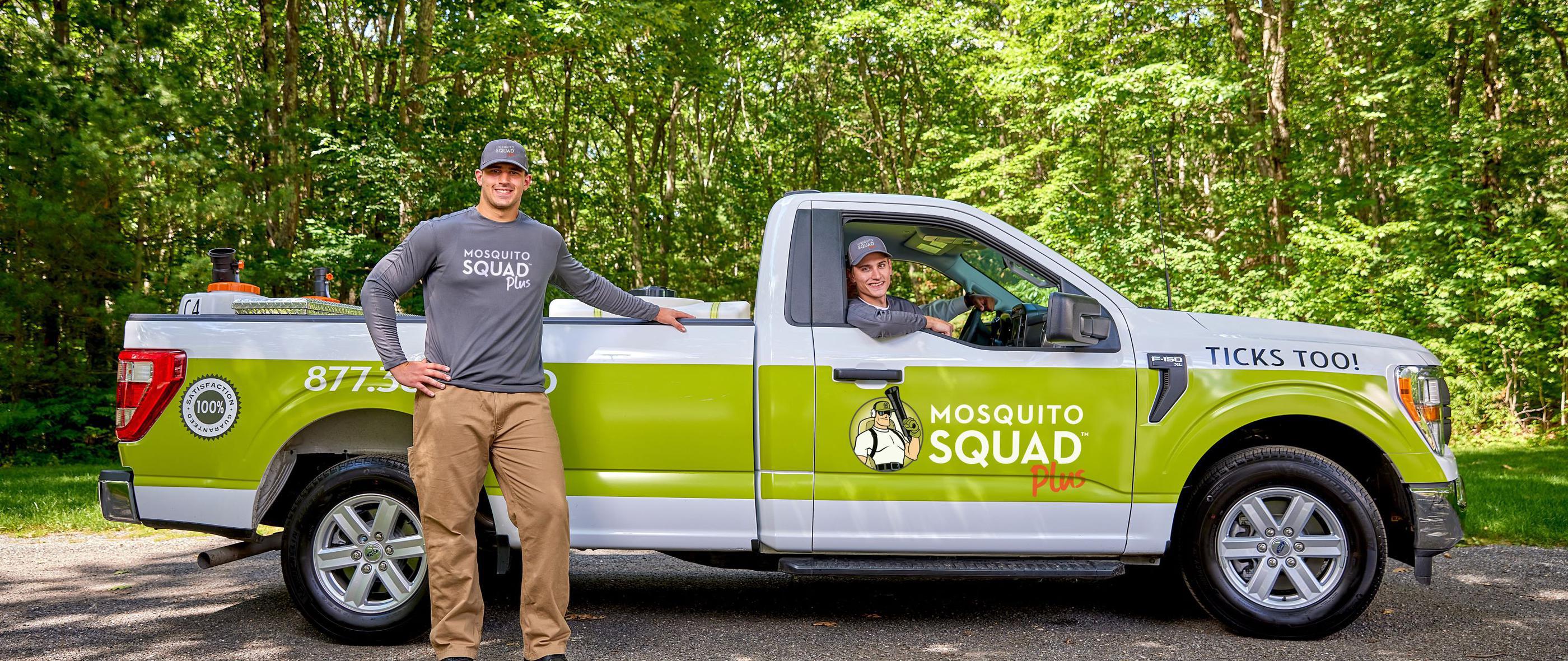 Mosquito Squad truck with bold branding for mosquito and tick control, parked outdoors with two team members ready for service.